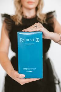 Woman holding a box of Radiesse collagen biostimulator injectable at Vibrant Med Spa in Louisville, Kentucky.